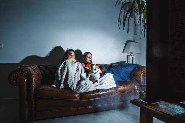 Dos niñas asustadas en un sofá viendo una película de terror.