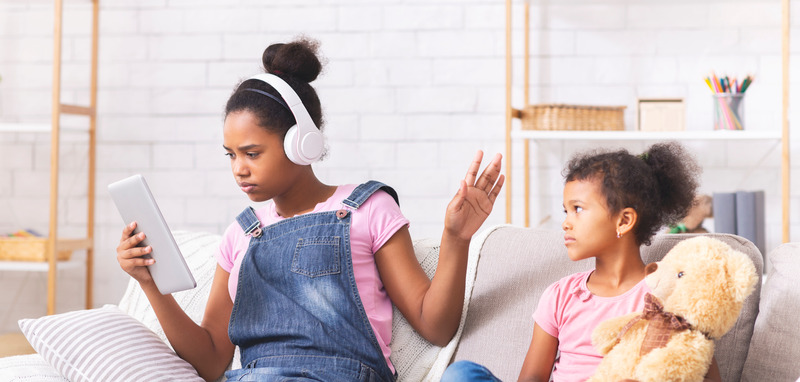 Imagen de dos personas, una adolescente y una niña, una de ellas ignora a la otra