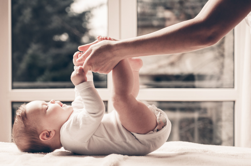 Un bebé en una mesa de cambio, tomando los brazos de su padre o cuidador