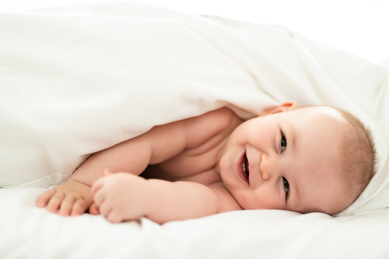 Bebé acostado en la cama con una expresión de felicidad